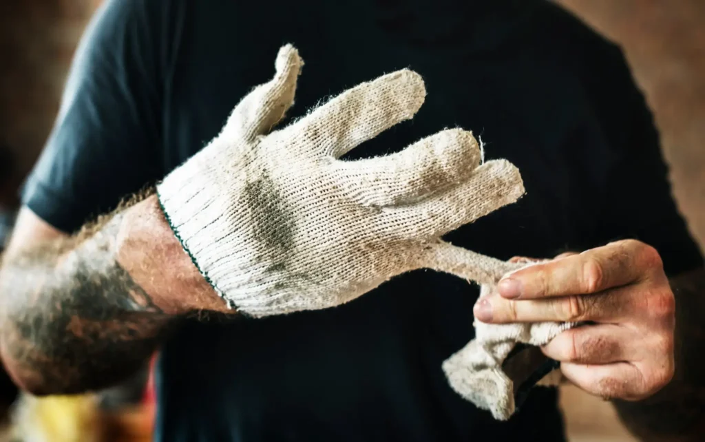 Outdoor Arbeiter zieht sich dreckigen Handschuh vom Finger